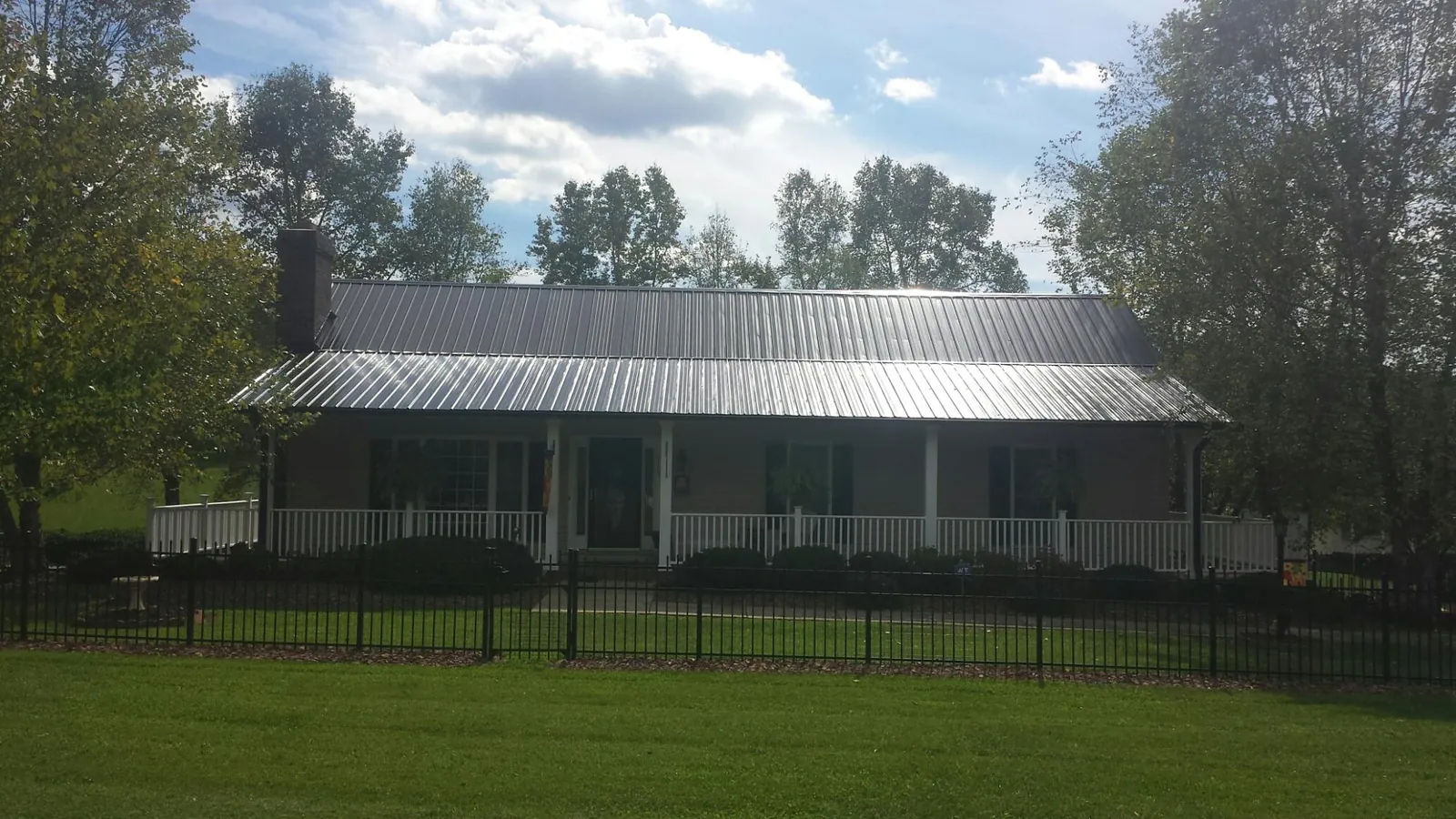 Gray metal roof on a brick ranch with a full width front porch — Gutter Guard Installation work by our crew in Hills